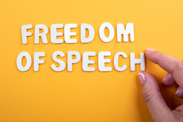 Freedom Of Speech. White letters and a woman's hand on a yellow background