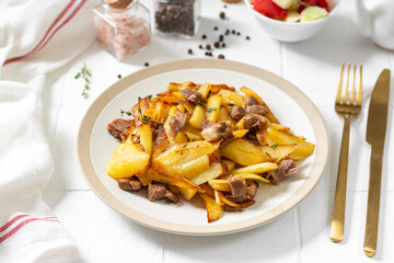 Fried potatoes with turkey meat and thyme in a plate on a white culinary background closeup