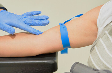 Fototapeta premium Nurse takes a blood sample, with a prick on the forearm of a patient. Rapid antibody diagnostic procedure.Steps in the process of a serology, antibodies and immunity