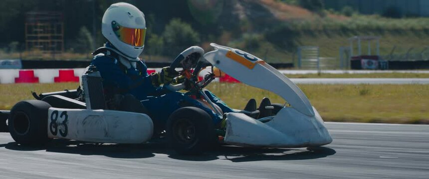 TRACKING Front view of teenager professional racer driving his go kart on a race track. Shot with 2x anamorphic lens