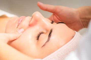 Fototapeta na wymiar Beautician making lymphatic drainage face massage or facelifting massage at the beauty salon