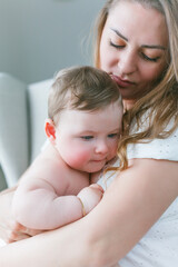 A beautiful young mother with a blue-eyed little daughter are resting at home. Cozy.
