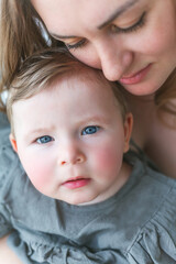A beautiful young mother with a blue-eyed little daughter are resting at home. Cozy.