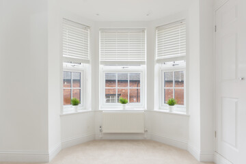 An empty modern room in an urban apartment with plain white walls and bay window - obrazy, fototapety, plakaty