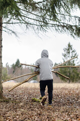 Forest clearing. A man carries a tree.