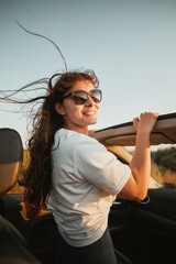 Attractive smiling woman wearing sunglasses in a convertible car. Concept of summertime journey and...