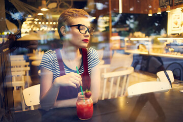 woman with glasses sitting at a table in a cafe with a cocktail drink leisure lifestyle