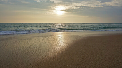 Mesmerizing seascape with a sandy beach under a cloudy sky at sunset