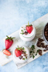 Healthy breakfast or dessert with natural yogurt, chocolate granola and strawberries. Top view.