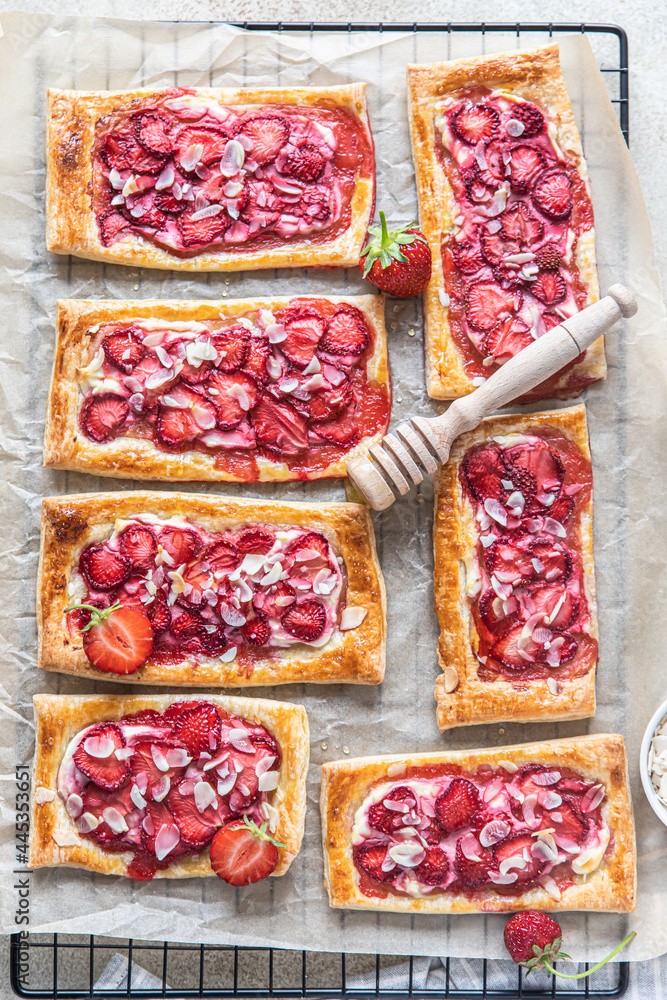 Poster Strawberry, cream cheese and almond puff pastry pies on baking paper. Top view.