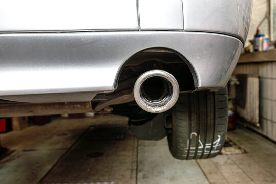 The exhaust system in the car seen from below, visible exhaust tip, the car is on the lift in the car workshop.