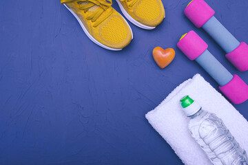 Fototapeta na wymiar sports at home - yellow sneakers, dumbbells and a bottle of water and a towel