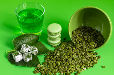 green Turkish delight and Macarons and pumpkin seeds on green background