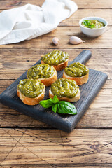Sandwiches with pesto sauce, fresh basil leaves and garlic. A delicious healthy snack. Wooden rustic background. copy space