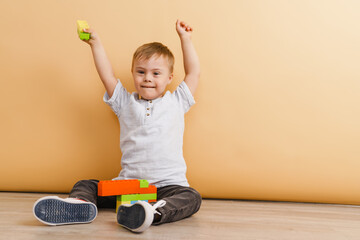 White boy with down syndrome playing while sitting on floor