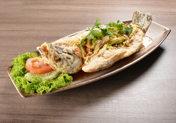 deep fried crispy whole grouper fish with mango salad dressing on wood background asian halal menu