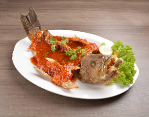 deep fried crispy whole grouper fish with spicy sambal chilli sauce on wood background asian halal menu