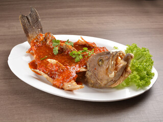 deep fried crispy whole grouper fish with spicy sambal chilli sauce on wood background asian halal menu