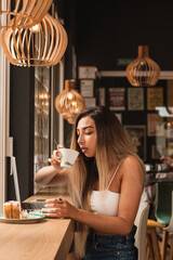 young beautiful woman eating a pie and working on the computer