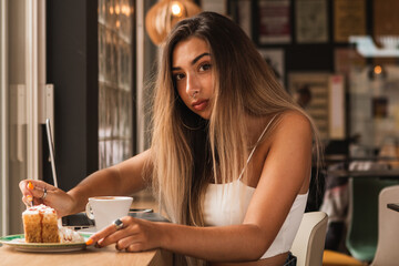 young beautiful woman eating a pie and working on the computer