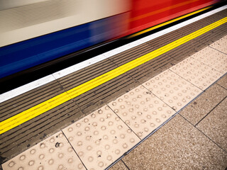 London Underground. A Central Line tube train passing the platform at speed to create an abstract background motion blur.