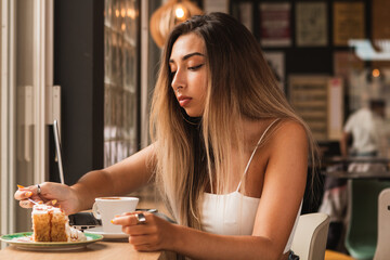 young beautiful woman eating a pie and working on the computer
