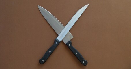 Two kitchen knives are lying cross-on-cross