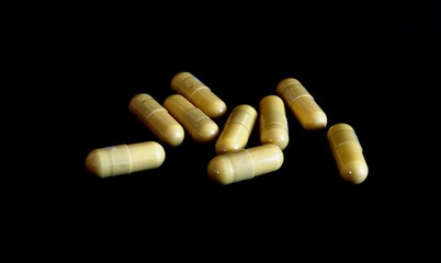Yellow capsules pills medicines on a black background