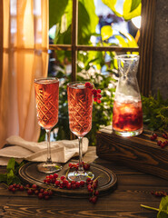 Two glasses of fresh cold currant cocktail on the table near the window, sunny backlight