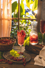Glass of fresh cold currant cocktail on the table near the window, sunny backlight.