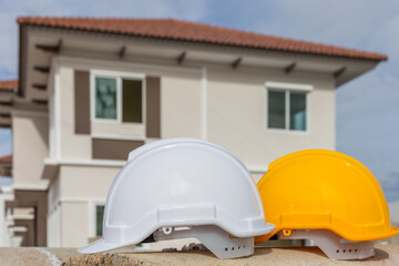 White, yellow hard safety helmet hat for safety project of workman as engineer or worker, house construction background.