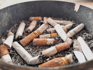 Cigarette butts in an iron ashtray placed on a concrete floor