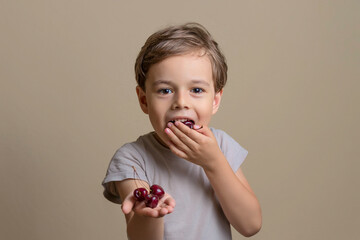 handsome and happy boy eating ripe, sweet, juicy, fresh cherries. little child holding cherries. Concept of healthy food. soft focus