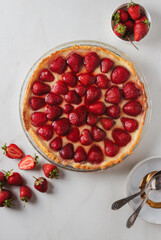Homemade strawberry custard tart decorated with strawberry on marble background. Top view 