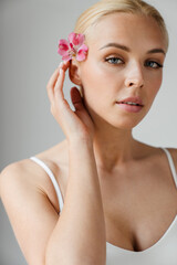 Young blonde woman looking at camera while posing with flower