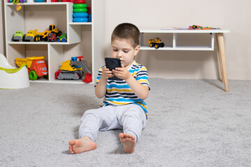 A little boy 3-4 years old looks into the phone screen. Cartoons for children, screen time,...