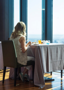 Mujer sola desayunando en un restaurante de lujo con vistas a la ciudad