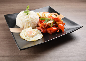 stir fried chicken meat in sweet and sour sauce with white rice and fried egg on wood background asian halal set lunch menu