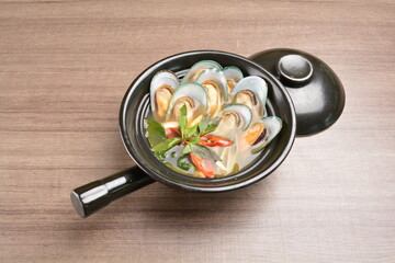 Thai hot spicy soup with muscle shell seafood and vegetable in clay pot on wood background asian halal set lunch menu