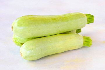 Green zucchini on a white wooden background