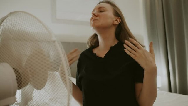 Woman tries to cool off during the intense heat in front of cooling fan.
