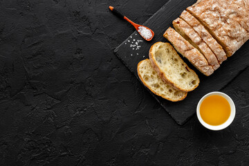 Sliced bread ciabatta with oil on cutting board, top view