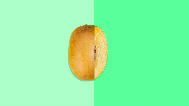 Stop motion animation. Ripe juicy kiwi moving along a line on a green background cuts in half then becomes whole again. Seamless video