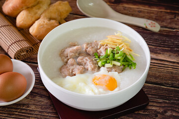 pork ball and boiled egg on top Chinese rice porridge (congee) as Asian breakfast on wooden background