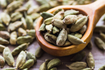 Green cardamom in a wooden scoop, aromatic spice used in the kitchen, providing many health benefits.
 - obrazy, fototapety, plakaty