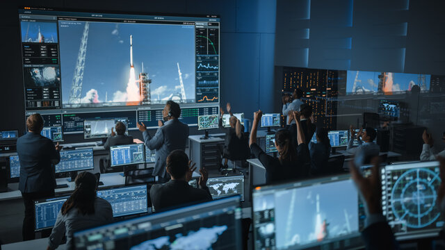 Group of People in Mission Control Center Witness Successful Space Rocket Launch. Flight Control Employees Sit in Front Computer Displays and Monitor the Crewed Mission. Team Stand Up and Clap Hands.