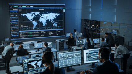 Shot of Officers in a Surveillance Control Center with Police Global Map Tracking on a Big Digital...