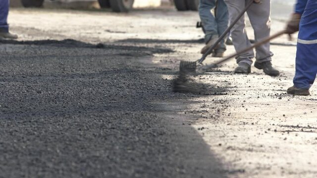 Telephoto shot of a road construction crew spreading fresh gravel on a road.