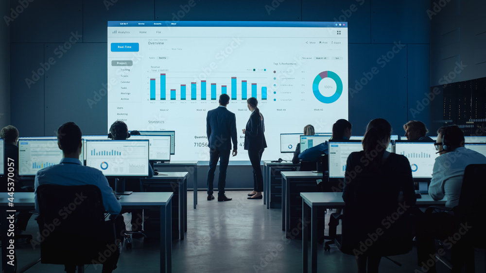 Aufkleber Two Traders Having a Meeting in a Modern Monitoring Office with Analytics Feed on a Big Digital Screen. Monitoring Room with Brokers and Finance Specialists Sit in Front of Computers. Colleagues Talk.