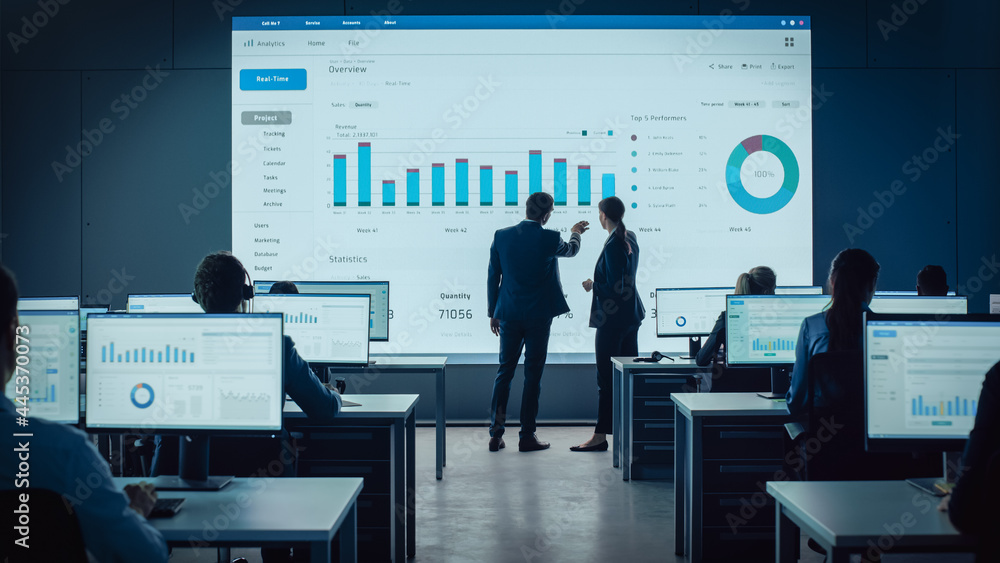 Poster Two Traders Having a Meeting in a Modern Monitoring Office with Analytics Feed on a Big Digital Screen. Monitoring Room with Brokers and Finance Specialists Sit in Front of Computers. Colleagues Talk.